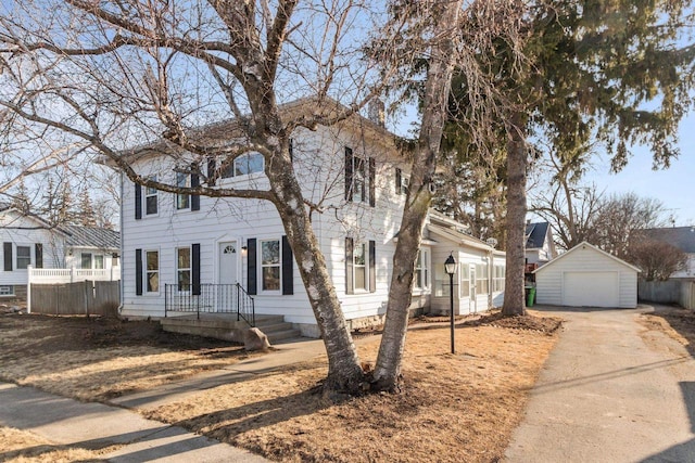 colonial house featuring an outbuilding, driveway, a garage, and fence