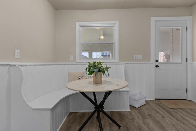 dining space with a wainscoted wall, breakfast area, and wood finished floors