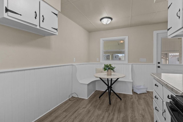 dining space featuring wood finished floors and a wainscoted wall