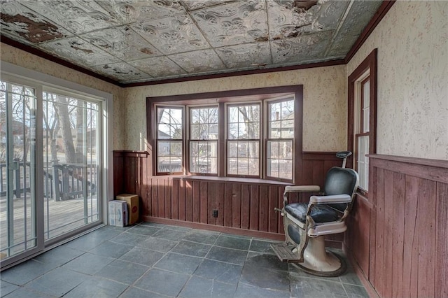 sitting room with a wealth of natural light, wainscoting, an ornate ceiling, and wallpapered walls