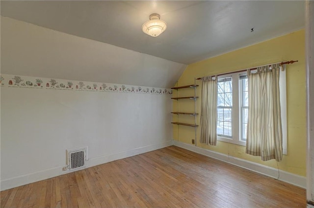 additional living space with visible vents, baseboards, lofted ceiling, and hardwood / wood-style flooring