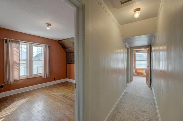 corridor with a wealth of natural light, baseboards, and vaulted ceiling