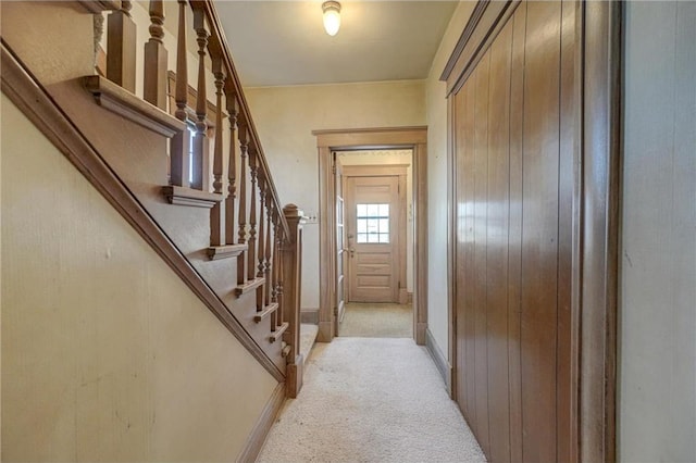 interior space featuring baseboards, light carpet, and stairs