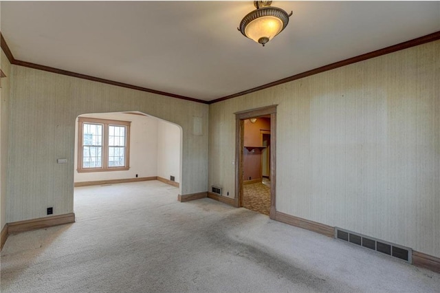 spare room with visible vents, wallpapered walls, crown molding, carpet flooring, and arched walkways