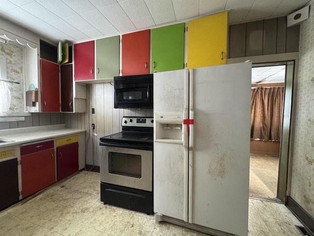 kitchen featuring light floors, electric range, white refrigerator with ice dispenser, black microwave, and red cabinets