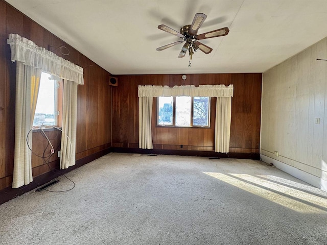 empty room with light carpet, wooden walls, and a ceiling fan