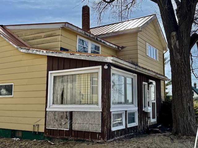 view of side of property featuring a chimney and metal roof