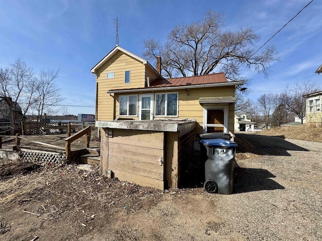 back of property with a deck, a standing seam roof, a chimney, and metal roof