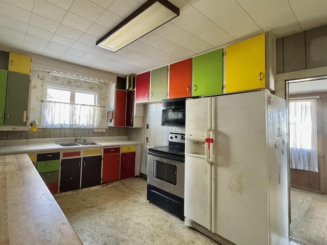 kitchen featuring stainless steel electric stove, white refrigerator with ice dispenser, plenty of natural light, and a sink