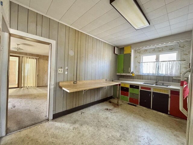 kitchen featuring wooden walls, light floors, light countertops, and a sink