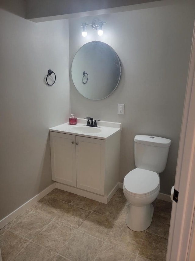 bathroom with baseboards, toilet, and vanity