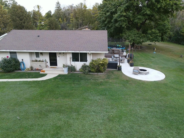 ranch-style house with a front lawn, a patio, an outdoor fire pit, roof with shingles, and a chimney