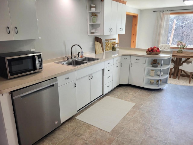 kitchen featuring open shelves, appliances with stainless steel finishes, light countertops, and a sink