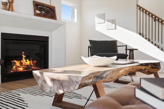 dining area with stairway, wood finished floors, and a glass covered fireplace