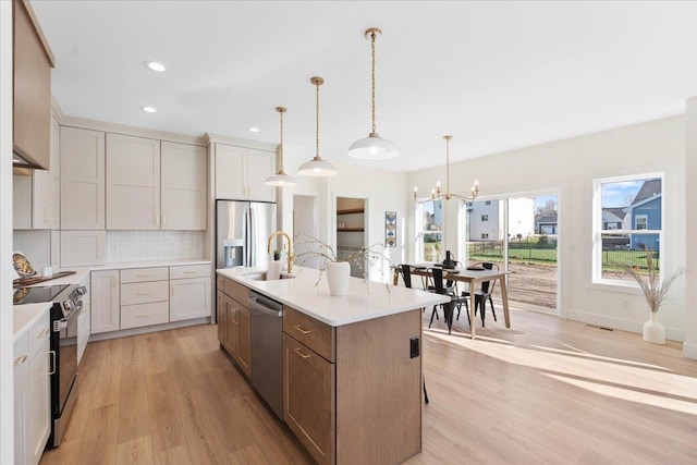 kitchen featuring a notable chandelier, a sink, stainless steel appliances, light countertops, and decorative backsplash