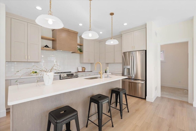 kitchen featuring a kitchen bar, wall chimney range hood, appliances with stainless steel finishes, and a sink