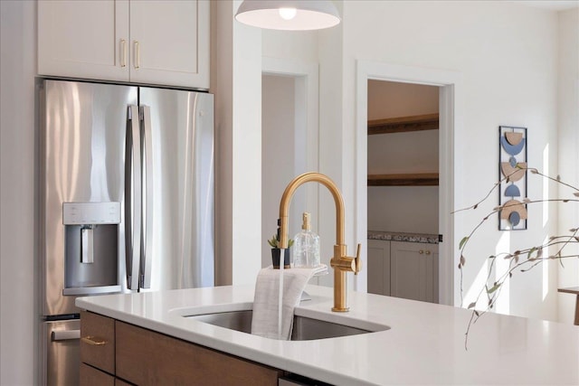 kitchen with light countertops, stainless steel refrigerator with ice dispenser, and a sink