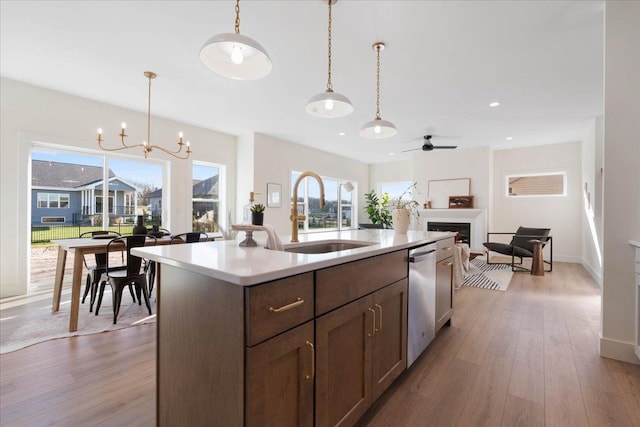 kitchen featuring decorative light fixtures, light countertops, a fireplace, hardwood / wood-style flooring, and a sink