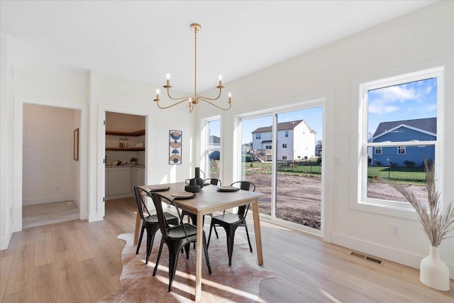 dining area with a chandelier, visible vents, light wood-type flooring, and baseboards