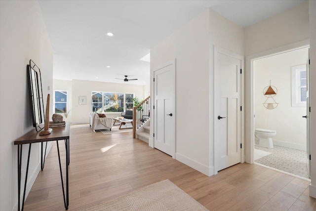 hallway featuring stairway, recessed lighting, light wood-type flooring, and baseboards