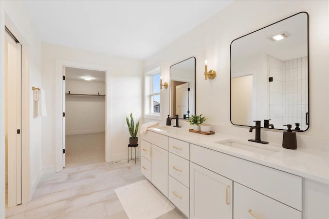 full bath featuring double vanity, visible vents, a walk in closet, and a sink