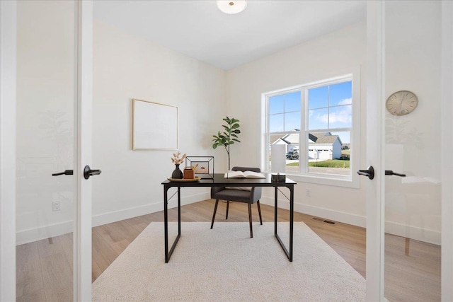 home office with wood finished floors, french doors, visible vents, and baseboards