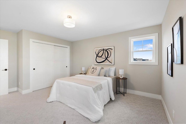 bedroom featuring light colored carpet, baseboards, and a closet