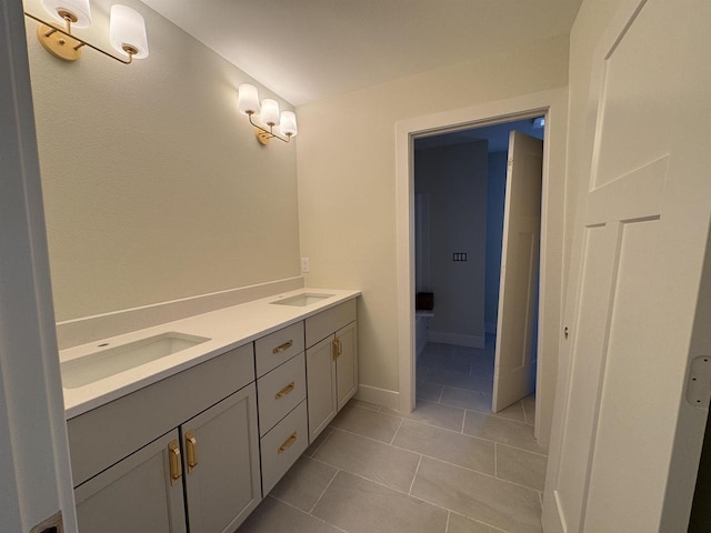 bathroom featuring double vanity, tile patterned floors, baseboards, and a sink