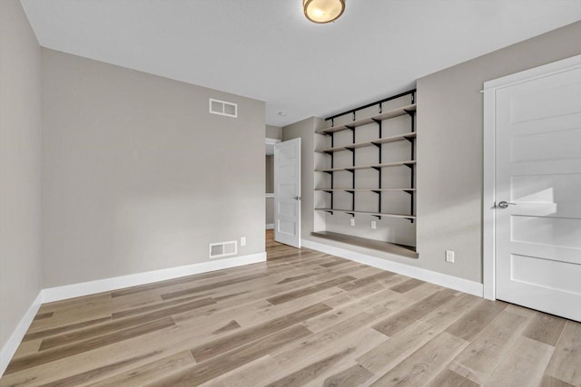 spare room with baseboards, visible vents, and light wood finished floors