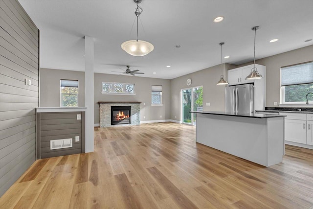 kitchen with dark countertops, freestanding refrigerator, light wood-style floors, white cabinets, and a healthy amount of sunlight