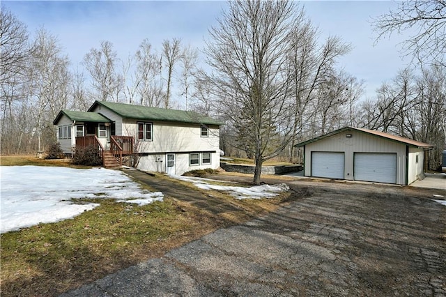 view of snow covered exterior featuring an outbuilding and a detached garage