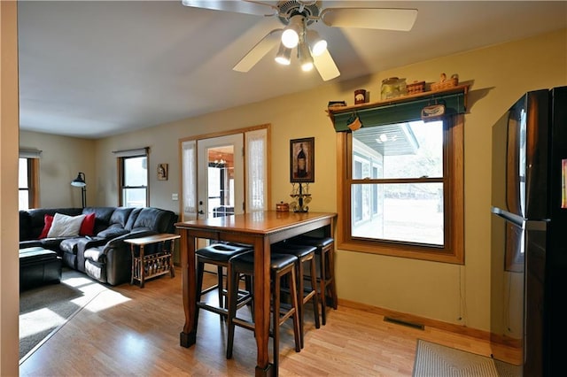 dining area with light wood-style flooring, a ceiling fan, and visible vents