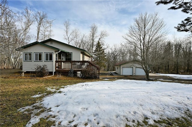 view of snow covered exterior featuring a garage, an outbuilding, and a deck