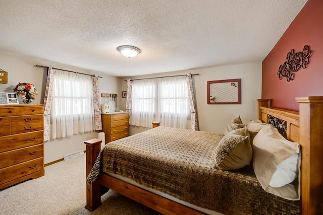 carpeted bedroom featuring multiple windows, baseboards, and a textured ceiling