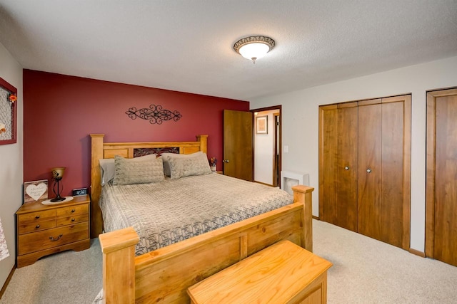 bedroom with multiple closets, carpet, and a textured ceiling