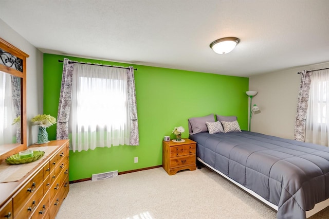 bedroom with an accent wall, carpet flooring, baseboards, and visible vents