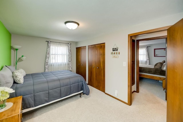 carpeted bedroom featuring multiple windows, baseboards, and multiple closets