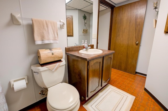 half bath featuring tile patterned floors, baseboards, toilet, and vanity