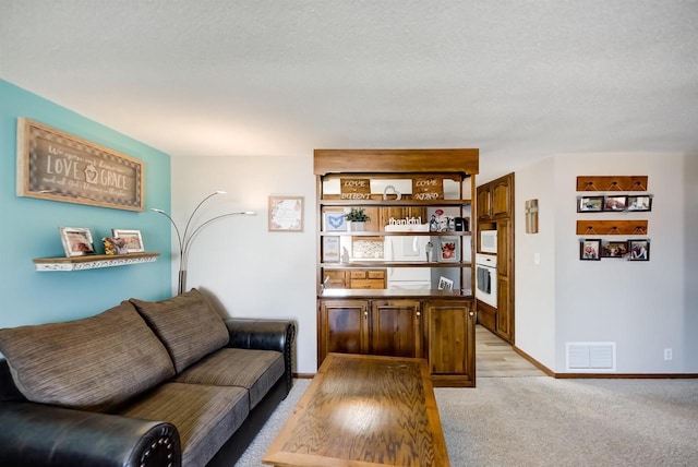 living room with visible vents, light carpet, and baseboards