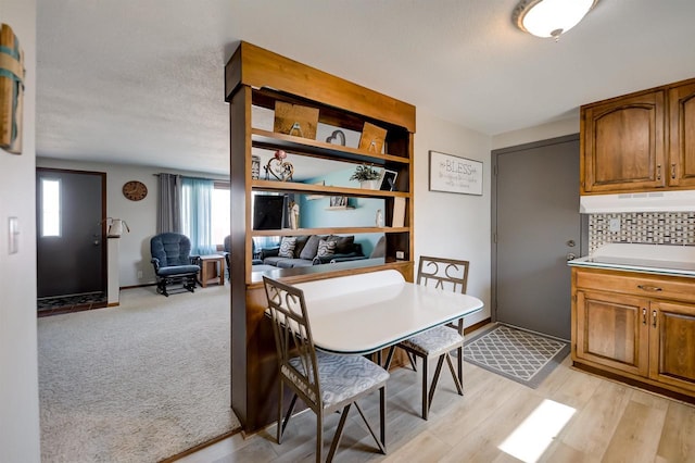 dining space with light wood-type flooring, light carpet, and a textured ceiling