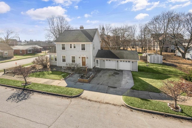 colonial house with driveway, a chimney, a front lawn, a garage, and a storage shed