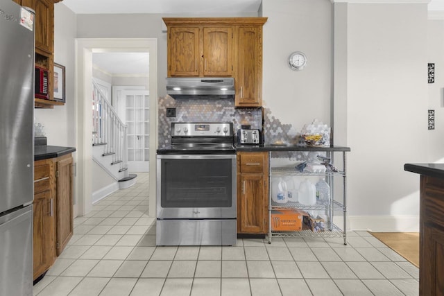 kitchen featuring under cabinet range hood, stainless steel appliances, dark countertops, and backsplash