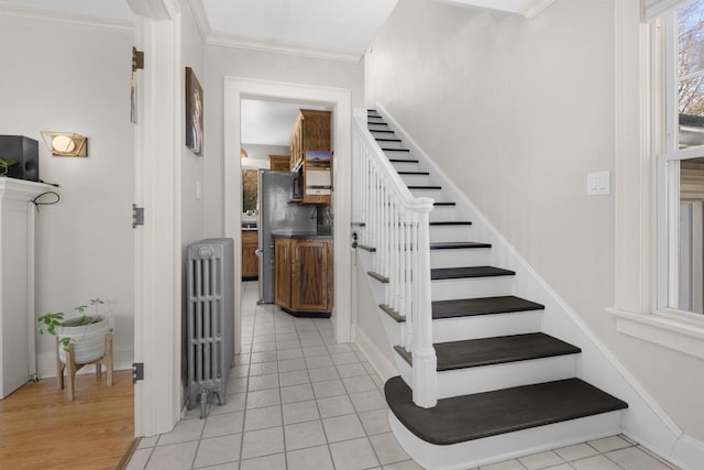 stairway featuring tile patterned flooring, radiator heating unit, and crown molding