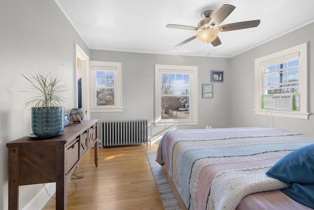 bedroom featuring a ceiling fan, crown molding, radiator, and wood finished floors