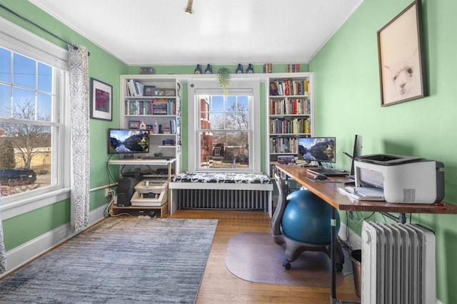 home office with crown molding, radiator heating unit, wood finished floors, and a wealth of natural light