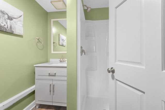 bathroom featuring baseboards, a stall shower, and vanity