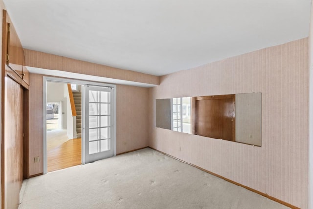 carpeted empty room featuring wallpapered walls and baseboards