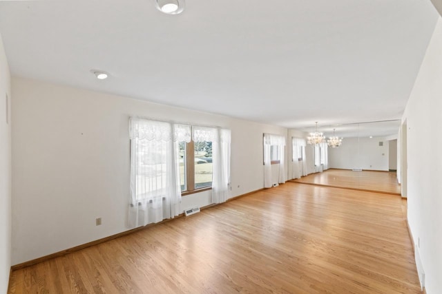 interior space with a chandelier, visible vents, baseboards, and light wood-style floors