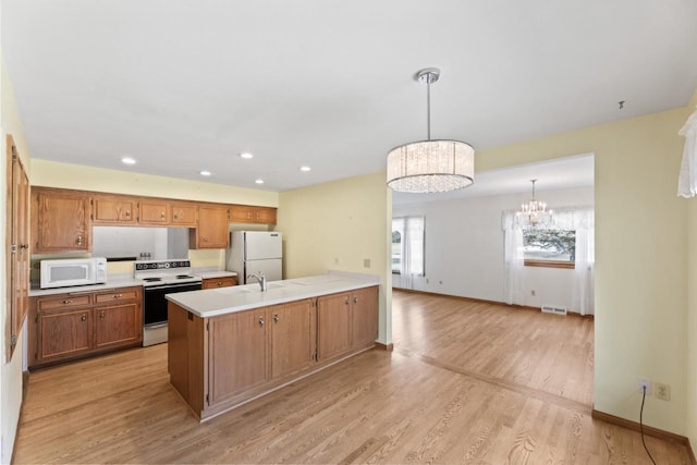 kitchen with visible vents, light countertops, a peninsula, a notable chandelier, and white appliances