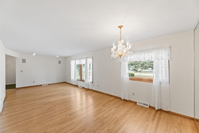 spare room featuring a notable chandelier, baseboards, visible vents, and light wood finished floors